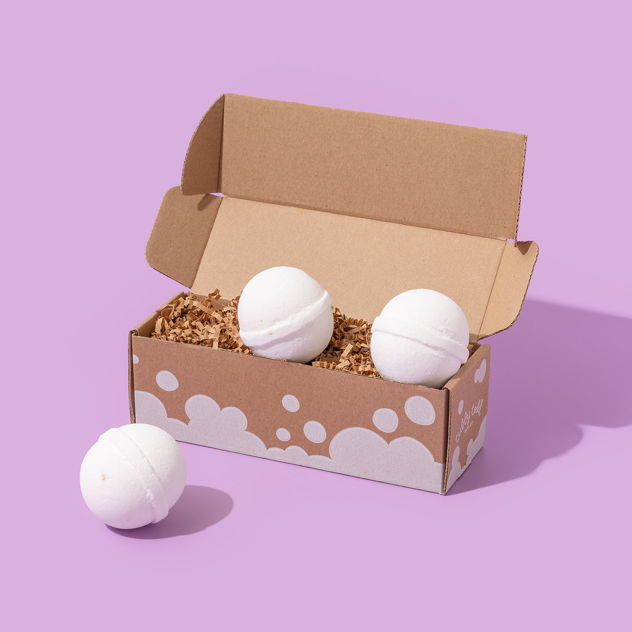 Oats Bath Bombs with the box standing on the purple background.
